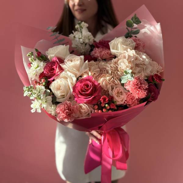 Bouquet of pink and white roses with carnations wrapped in pink paper