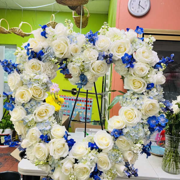 Heart-shaped floral wreath with white roses and blue flowers