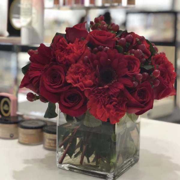 Red rose and carnation bouquet in a clear square vase