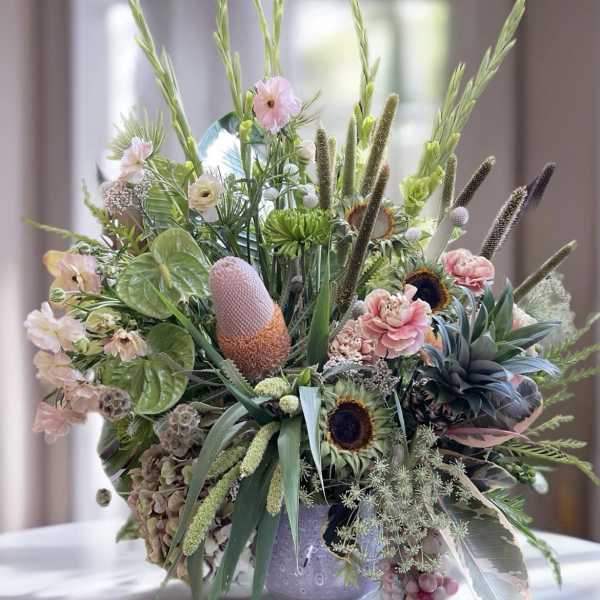 Large mixed floral arrangement in a decorative vase with pink and green blooms