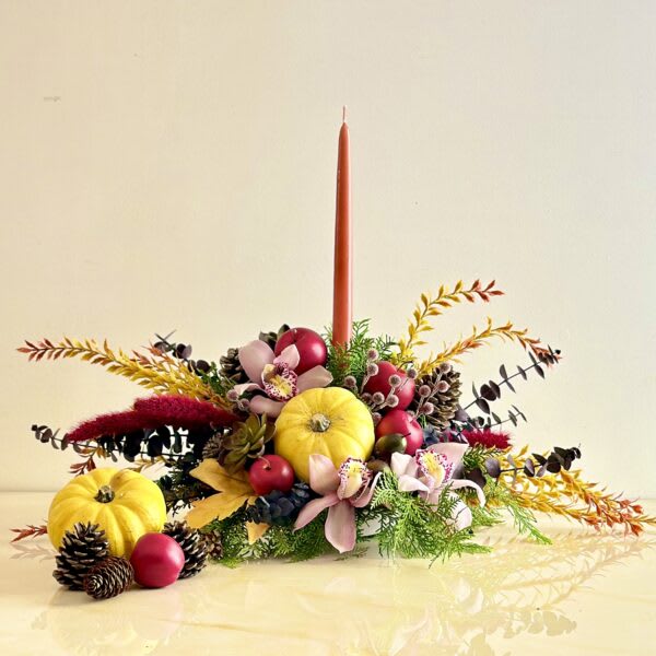 Autumn centerpiece with pumpkins, flowers, and a tall candle