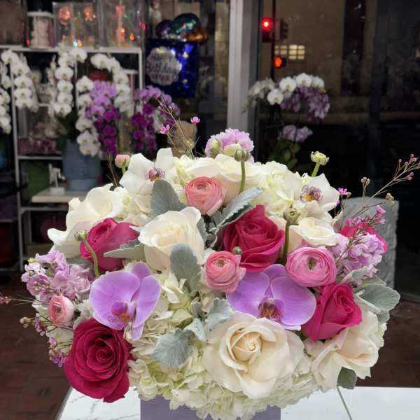 Bouquet of pink and white roses with orchids in a lavender box