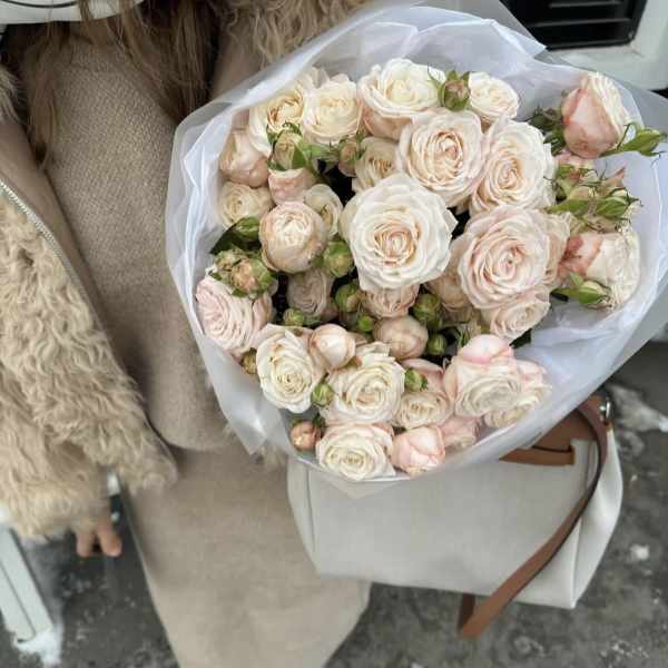Bouquet of pale pink and white roses wrapped in white paper