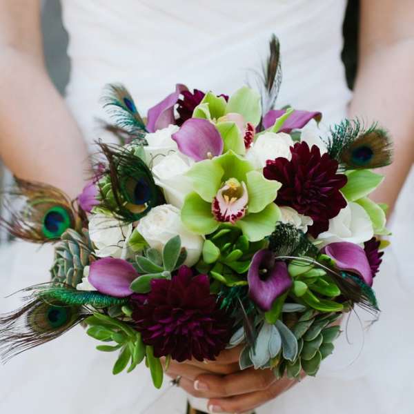 Bridal bouquet with purple calla lilies, white orchids, and peacock feathers