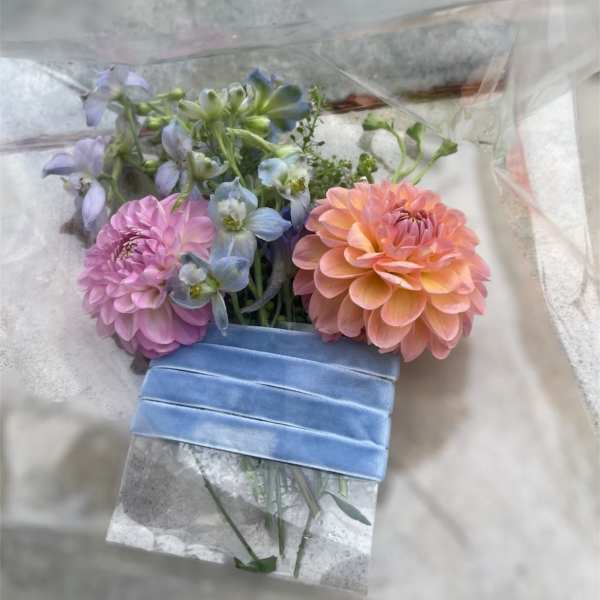 Bouquet of pink, peach, and blue flowers wrapped in clear plastic