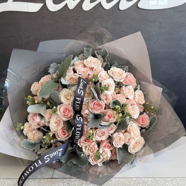 Bouquet of pale pink roses wrapped in translucent paper