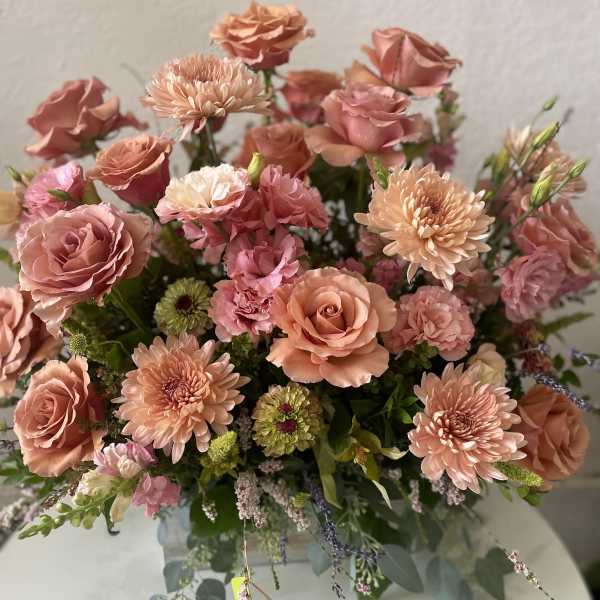 Peach and pink roses with chrysanthemums in a glass vase