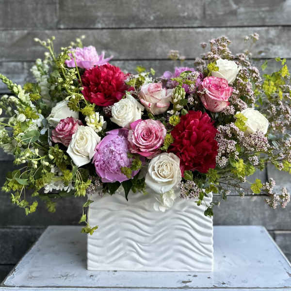 Mixed pink, white, and red flowers in a white textured vase