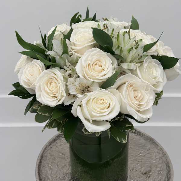 White roses and alstroemeria arranged in a green glass vase