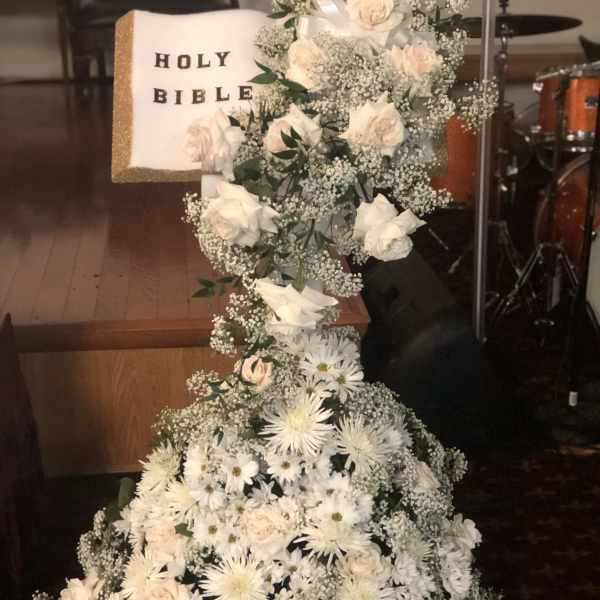 Tall white floral arrangement with a Holy Bible centerpiece