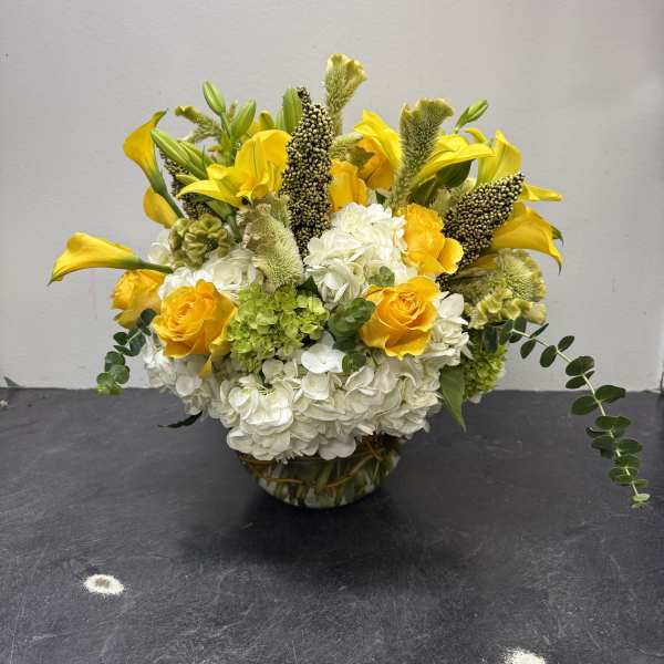 Yellow roses and white hydrangeas in a glass bowl vase