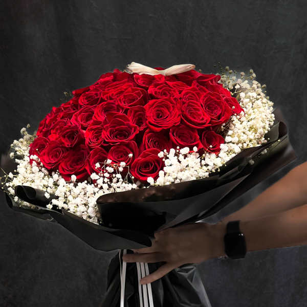 Bouquet of red roses with white baby's breath wrapped in black paper