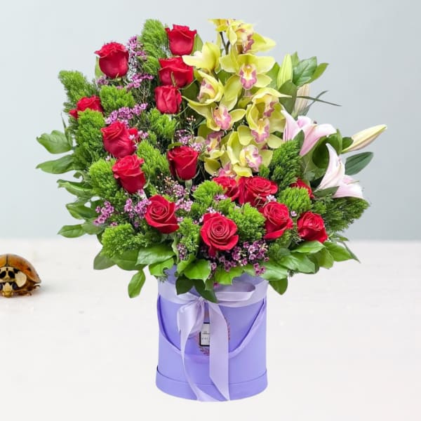 Bouquet of red roses and yellow orchids in a lavender box