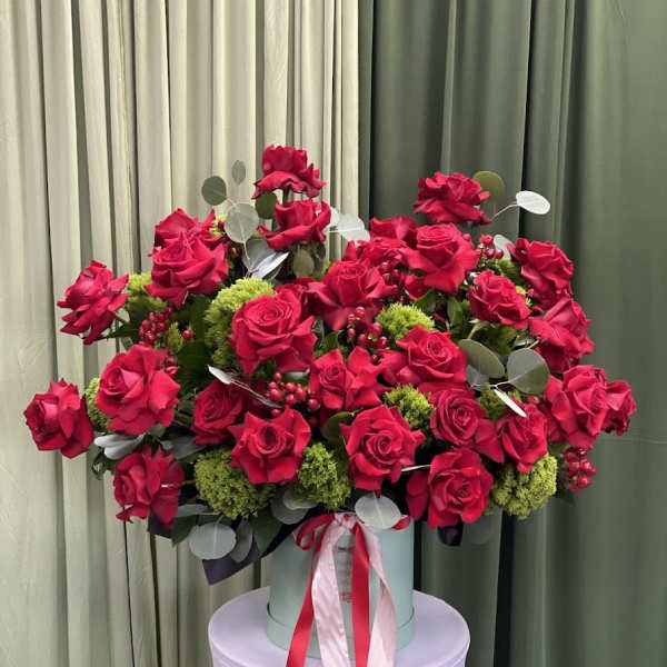 Large bouquet of red roses in a round box with ribbon