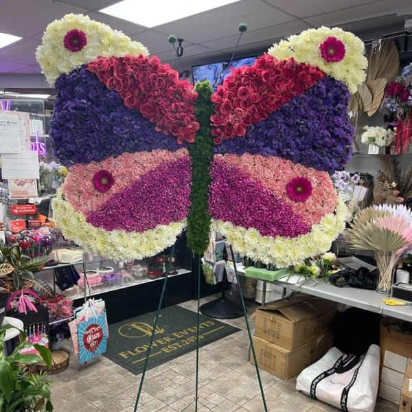 Butterfly-shaped floral display on a stand with purple and pink flowers
