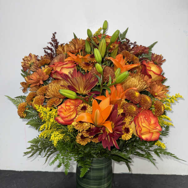 Autumn bouquet of orange and burgundy flowers in a green glass vase