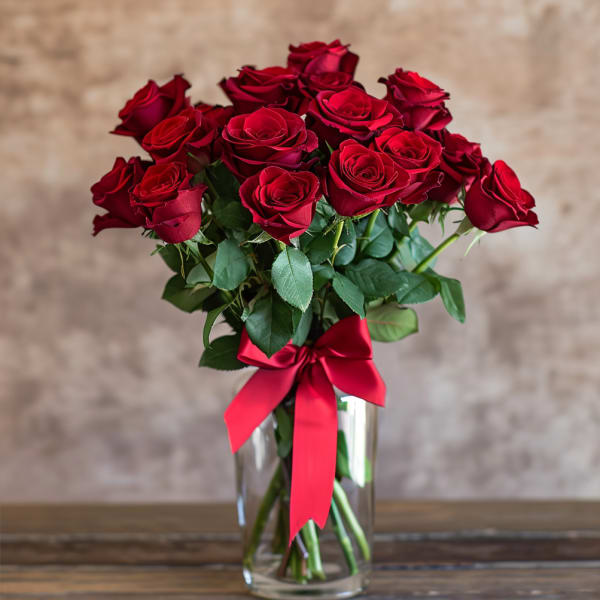 Bouquet of red roses in a clear glass vase with a red ribbon