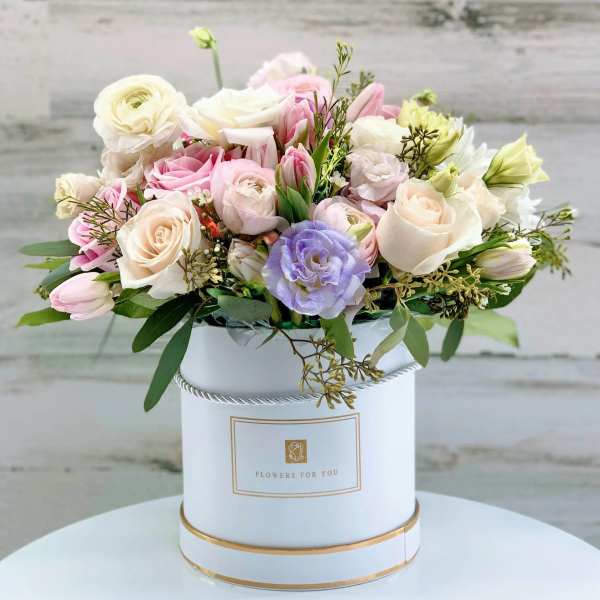 Pastel bouquet of roses and tulips in a white hatbox