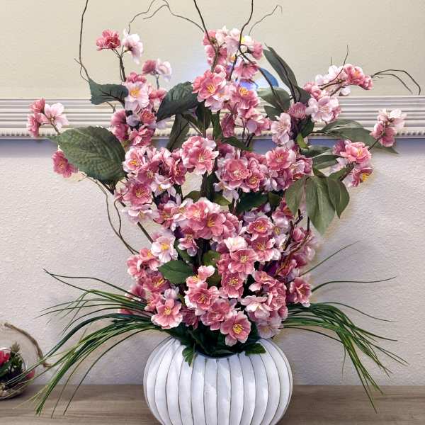 Pink blossoms arranged in a white ribbed vase with tall branches