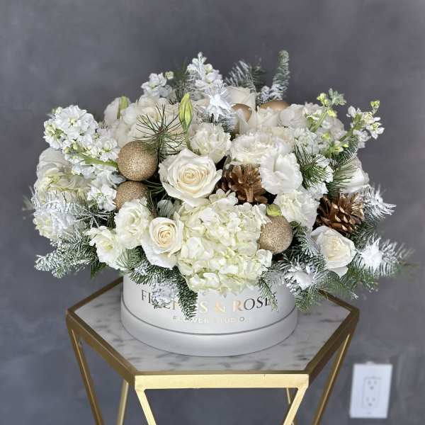 White floral arrangement with roses and hydrangeas in a round box