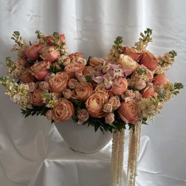 Large peach and cream floral arrangement in a white textured vase