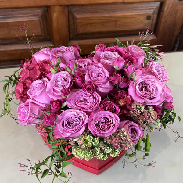 Pink rose arrangement in a red box with small accent flowers