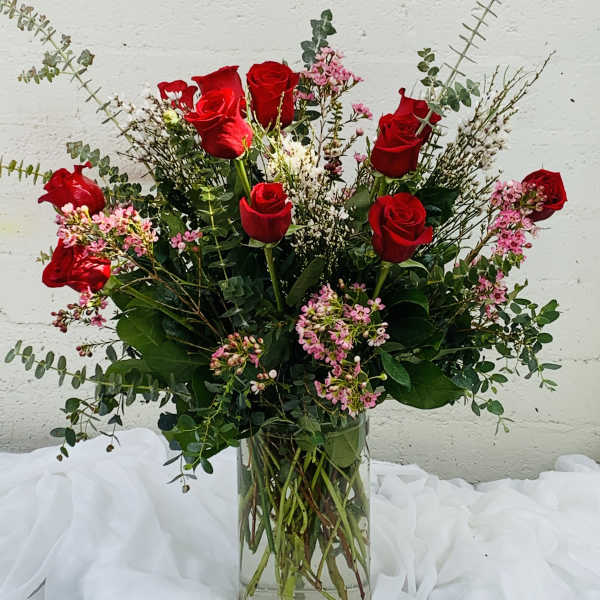 Red roses in a clear glass vase with pink filler flowers