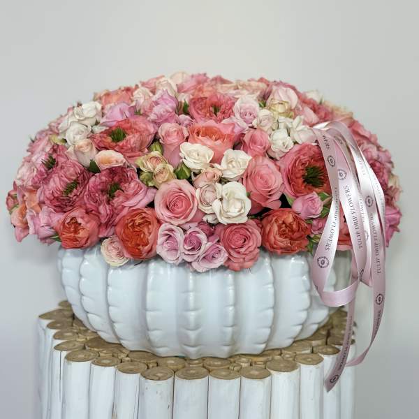 Pink and white rose arrangement in a white pumpkin-shaped vase with ribbon