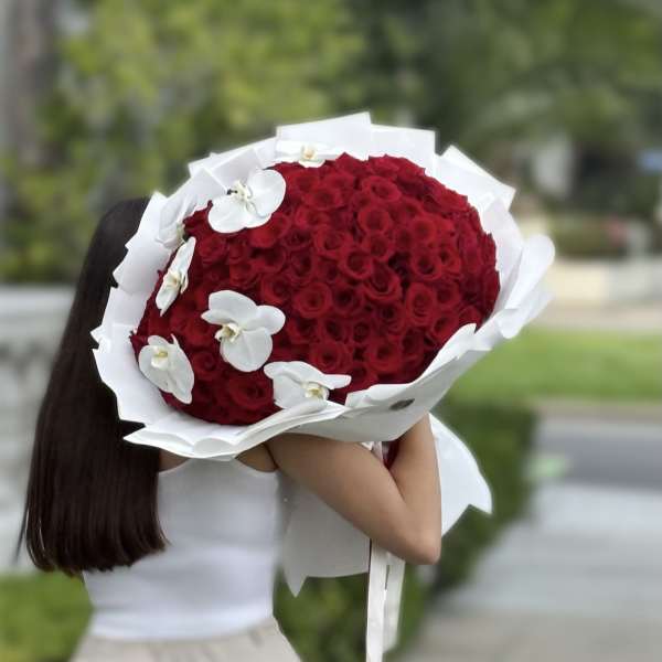 Large bouquet of red roses with white orchids wrapped in white paper
