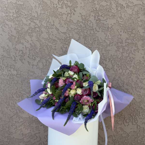 Bouquet of pink, white, and purple roses wrapped in lavender paper