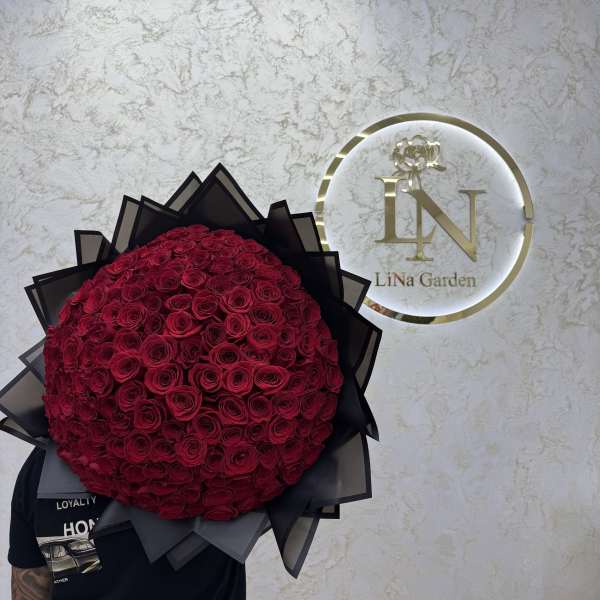 Large round bouquet of red roses wrapped in black paper