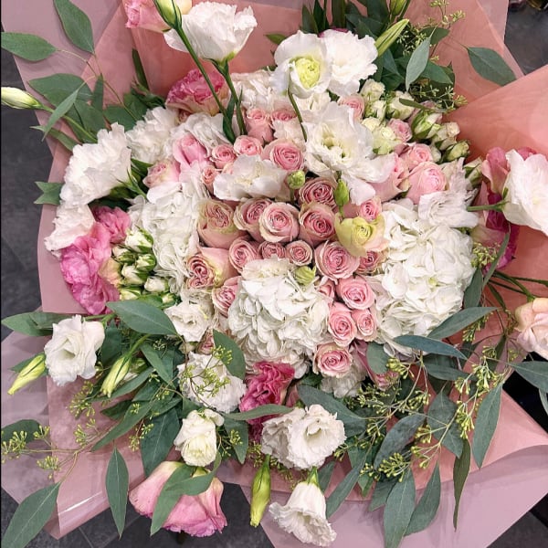 Bouquet of pink and white roses with white blooms wrapped in pink paper