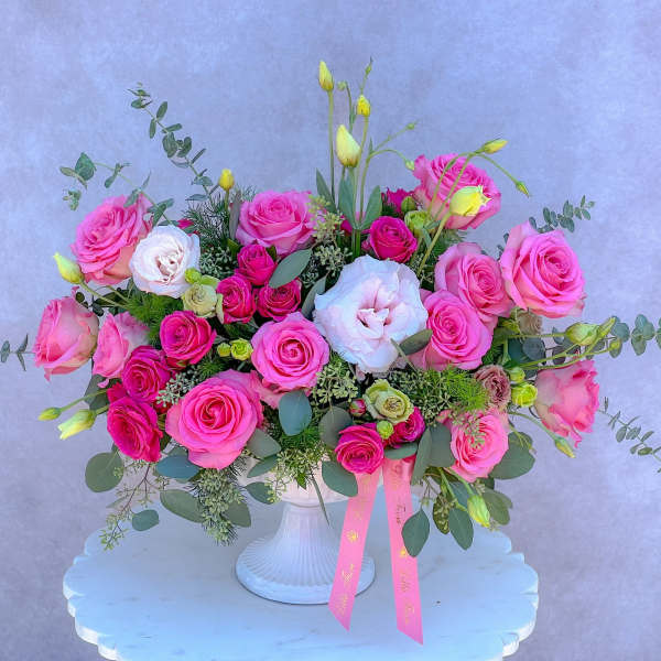 Pink rose bouquet in a white vase with eucalyptus and ribbon