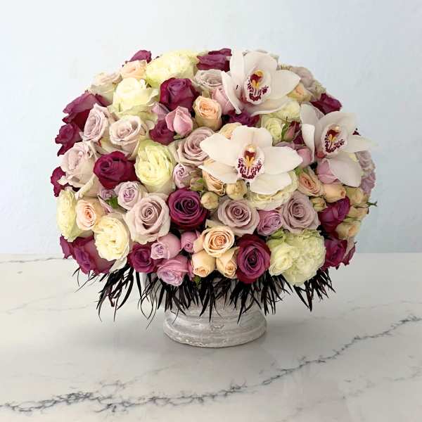 Large bouquet of roses and white orchids in a low pedestal vase