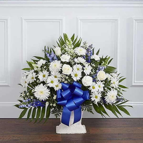 White floral standing spray with a blue ribbon on a pedestal base