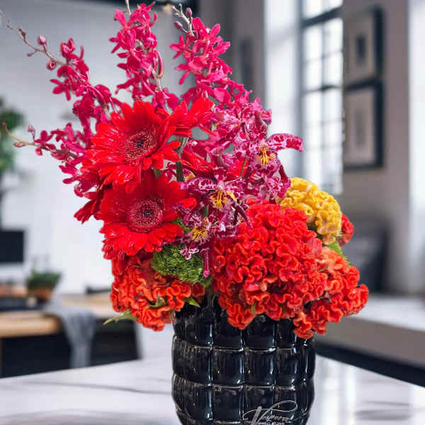 Bright red and pink floral arrangement in a black vase