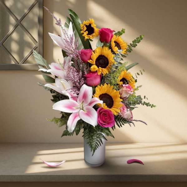 Bouquet of sunflowers, pink roses, and lilies in a white vase