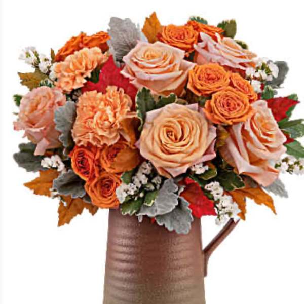Orange and peach rose bouquet in a brown pitcher vase