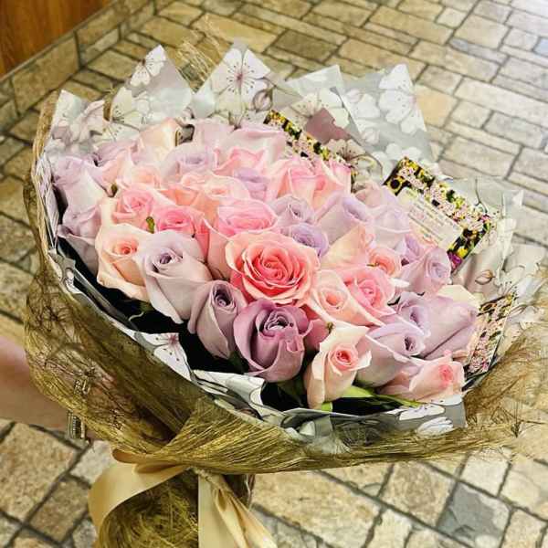 Bouquet of pastel pink and lavender roses wrapped in decorative paper