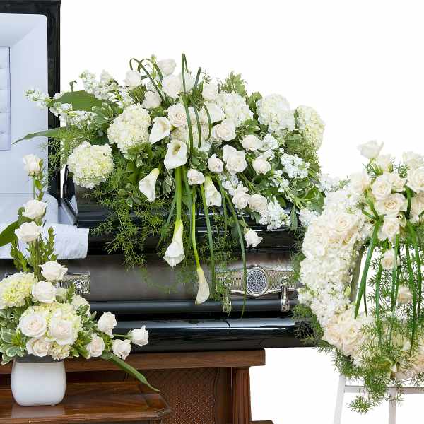 White funeral casket spray with roses, calla lilies, and hydrangeas