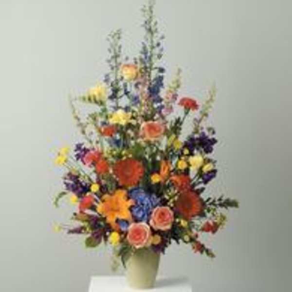 Tall mixed flower arrangement in a pale vase