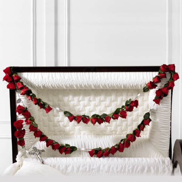 White casket with red rose garlands draped across the top
