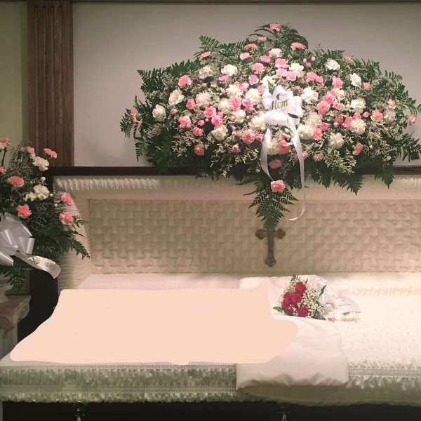 White casket with pink and white floral sprays