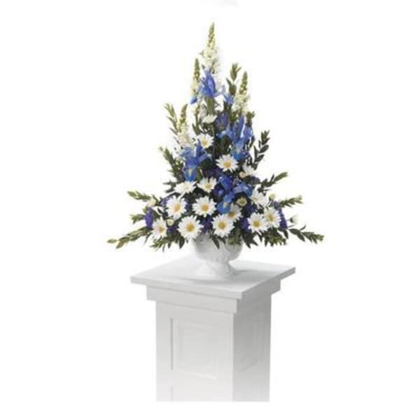 Blue and white floral arrangement in a white urn on a pedestal