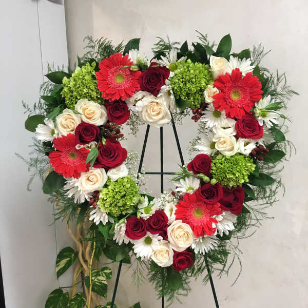 Heart-shaped floral wreath with red roses, white daisies, and green hydrangeas