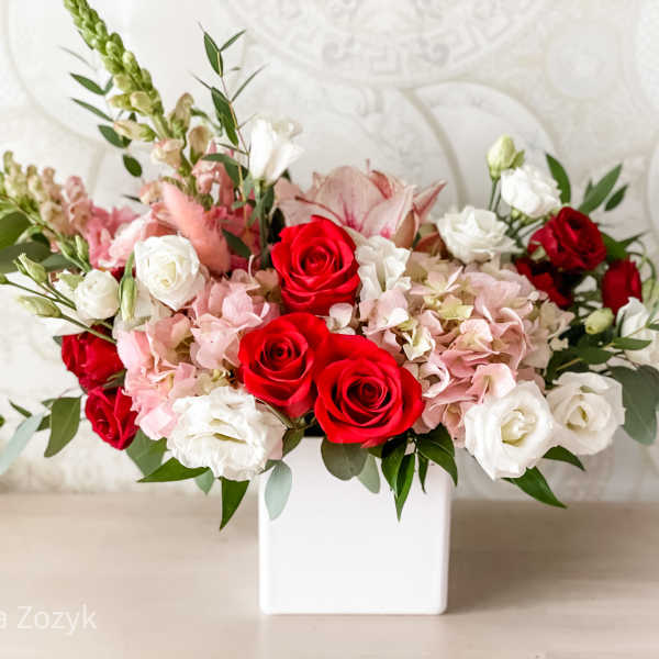 Red and white roses with pink blooms in a white vase