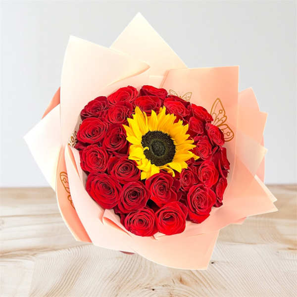 Bouquet of red roses with a sunflower center wrapped in peach paper