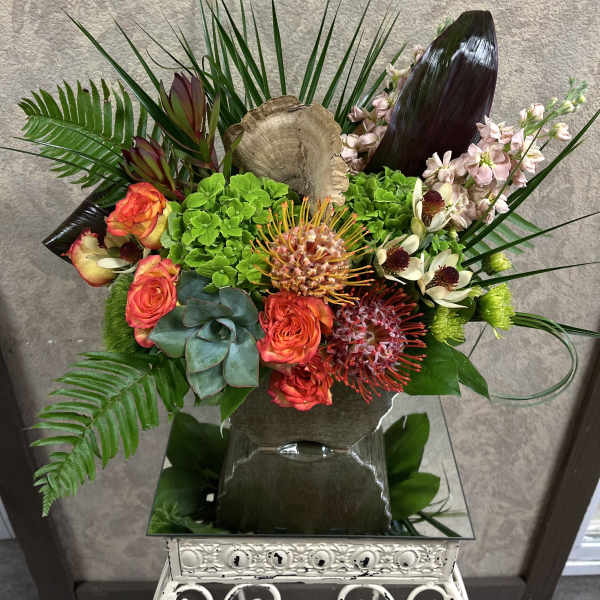 Tropical floral arrangement with orange roses and green hydrangea in a vase