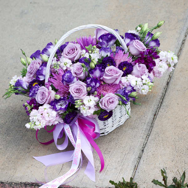 White basket of purple and lavender flowers with ribbon