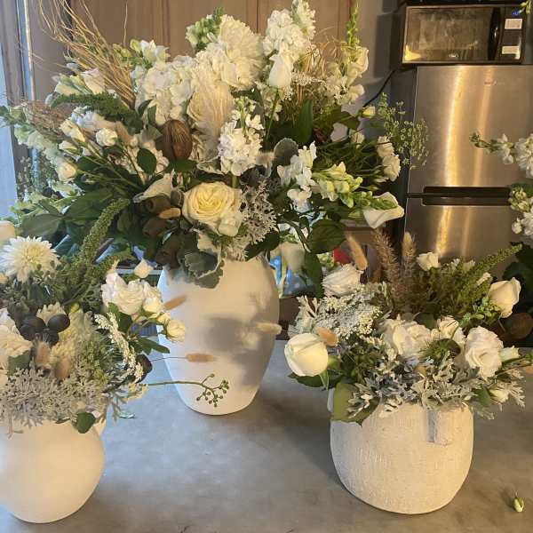 White floral arrangements in ceramic pitchers and vases